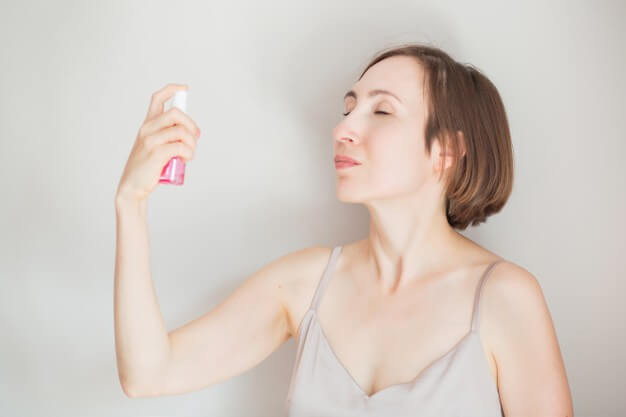 Brunette woman applying face tonic isolated