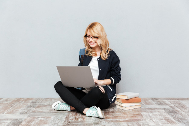 Cheerful young woman student using laptop computer