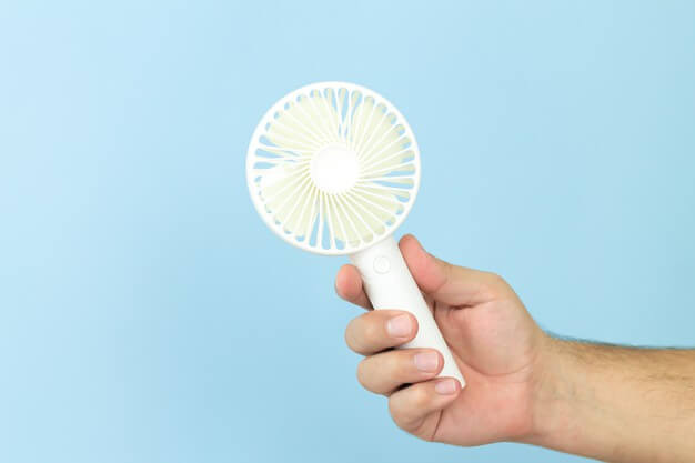 Man holding small portable usb fan close-up isolated